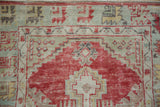 Worn texture on a vintage Oushak rug's stepped cherry red medallion and seafoam green corner.