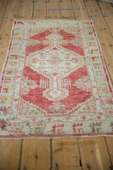 Angled view of a distressed Oushak rug, highlighting its low-pile texture and geometric red medallion.