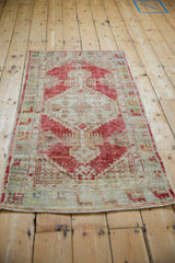 Angled view of a distressed Oushak rug showing its stepped cherry red medallion.