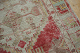 Distressed texture of a vintage Oushak rug, showing low pile and faded red geometric patterns.
