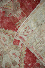 Corner of the distressed Oushak rug folded to show its hand-knotted foundation.