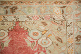 Distressed texture on the floral corner spandrel of a vintage Oushak rug in faded tones.