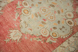 Corner detail of a distressed Oushak with floral spandrels in faded cherry red and dusty blue.