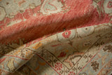 Soft, low pile of a distressed Oushak rug showing time-softened red and powder blue tones.