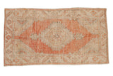 Vintage distressed Oushak rug with a pale cantaloupe diamond medallion on a sandy beige field.