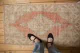 Vintage distressed Oushak rug showing its low, worn pile and cantaloupe geometric medallion.