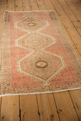 Distressed vintage Kars rug corner with dusty blush field, detailed zig-zag border, even wear.