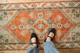 Overhead view of the distressed Oushak runner's rust medallion and pale mint green details.