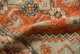 Low-pile texture and geometric motifs in rust and charcoal teal on a folded Oushak rug.