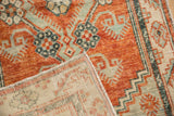 A corner folded back reveals the hand-knotted foundation of a distressed Oushak rug.
