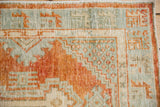 Worn hand-knotted pile showing geometric border motifs in tangerine orange and powder blue.