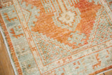 Corner view of a distressed Oushak rug's low pile, showing geometric patterns in pale rust and powder blue.