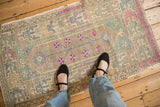 Distressed Oushak rug showing a low pile with a mauve, mint, and fuchsia color palette.