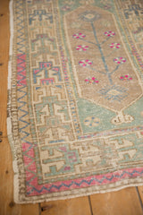 Geometric border and mint green spandrel on a distressed vintage Oushak with low-pile wear.