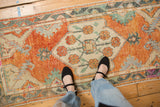 Decorative vintage Oushak runner, with time-softened rust orange and seafoam green floral designs.