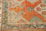Distressed Oushak runner corner with aged rust, seafoam green, and ivory primitive patterns.
