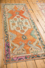 Visible distressed texture with a vibrant magenta zigzag border on a vintage Oushak runner.