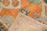 Distressed Oushak rug pile in vivid rust orange, seafoam green, and cream, revealing its woven back.