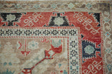 Corner detail of a distressed Anatolian rug with serrated red, black, and turquoise geometric borders.