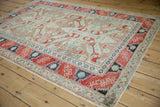 Distressed Anatolian rug from an angle, showing layered borders with cherry red and deep navy motifs.