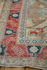 Angled view of the distressed Anatolian rug's cherry red serrated border and starburst motifs.