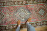 Distressed Oushak runner with geometric blush, mint, and bronze patterns, its worn texture underfoot.