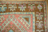 Distressed vintage Oushak rug border showing hook and latch motifs in blush, mint, and brown.