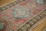 Distressed vintage Oushak runner with blush, blue, and mint geometric motifs and worn pile.