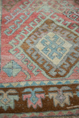 Distressed Oushak runner's geometric hook and latch patterns in blush, mint, bronze, and ivory.