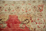 Detail of the distressed, low-pile weave showing pomegranate red and brown serrated leaf motifs.