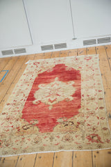 Angled perspective of a distressed Anatolian rug with a pomegranate red and ivory design.
