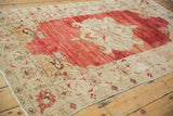 A long perspective of a distressed Anatolian rug, highlighting its abrashed red field and ivory design.
