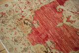 Distressed vintage Anatolian rug detail showing abrashed red pile and decorative sand-colored corner spandrels.