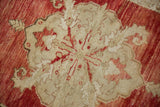 Detailed texture of the central medallion showing even wear across the pomegranate red and ivory knot heads.