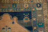 Corner detail of a distressed Oushak rug showing navy spandrels and primitive teal motifs on a worn pile.