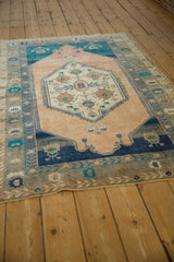 A distressed Turkish Oushak rug viewed at an angle, showing the full medallion and border design.
