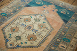 Primitive floral medallion and deep teal corner spandrel on a distressed vintage Oushak rug.