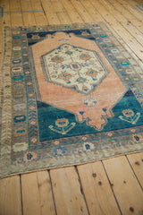 Angled perspective of a distressed Oushak rug, showing the interplay of sandalwood, teal, and navy.