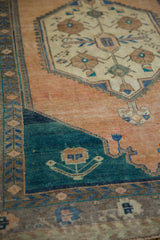 Deep teal corner spandrel beside the abrashed sandalwood field on a vintage Oushak rug.