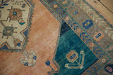 Corner detail of a distressed Oushak rug showing the finned vine border and teal spandrel.
