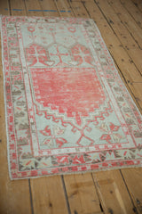 High-angle view of a distressed Oushak runner with a geometric prayer design in faded red and seafoam green.