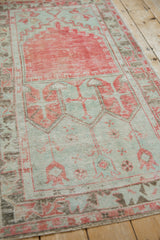Angled view of a distressed Oushak runner's prayer design and geometric field in red and seafoam.