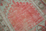 Close-up of the Turkish Oushak's prayer design in faded red and its geometric seafoam green border.