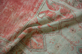 Softly draping distressed Oushak rug with low-pile texture in faded red and seafoam green.