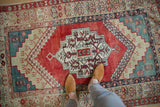 A view from above showing the scale of a distressed Anatolian rug's ruby red, stepped medallion.