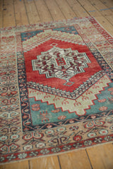 Angled view of a vintage Anatolian rug's abrashed ruby red field and central stepped medallion.
