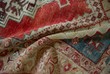 A textural close-up of a distressed Anatolian rug's soft pile and ruby, teal, and beige hues.