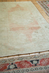 Angled view showing the abrashed ground and low-pile texture of the distressed Oushak runner.