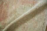 A folded view showing the distressed Oushak's worn pile, visible white knots, and soft texture.
