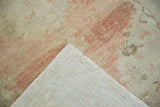Hand-knotted ivory foundation and low, abrashed pile visible on the vintage Oushak's corner.